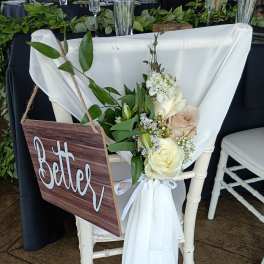 White chair with a floral arrangement and a wooden "Better" sign