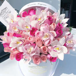 Pink and white bouquet of roses and orchids in a white hat box