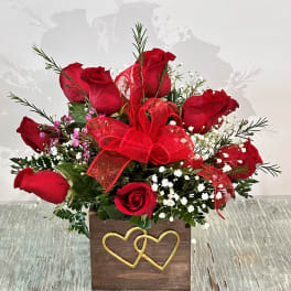 Red roses in a wooden box with a red bow and gold heart decoration