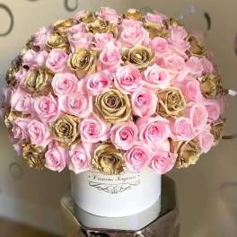 Round bouquet of pink and gold roses in a white hat box