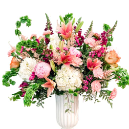 Large mixed flower arrangement in a white pedestal vase