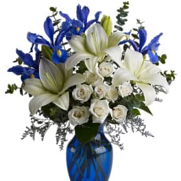 White lilies, blue irises, and white roses in a blue glass vase