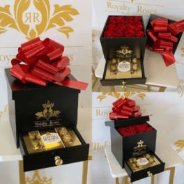 Black gift box with red roses and a red bow, plus chocolates in a drawer.