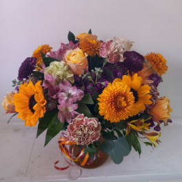 Mixed bouquet with orange sunflowers and purple blooms in a vase