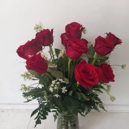 Red roses arranged in a clear glass vase with white filler flowers
