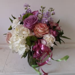 Bouquet of pink, white, and lavender flowers with ribbon in a glass vase