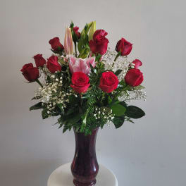 Red roses and pink lilies in a purple glass vase