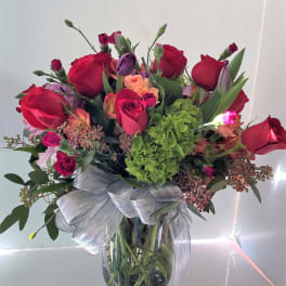 Bouquet of red roses and mixed flowers in a glass vase with a silver ribbon