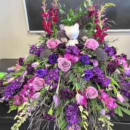 Large purple floral spray with roses and a white cat figurine