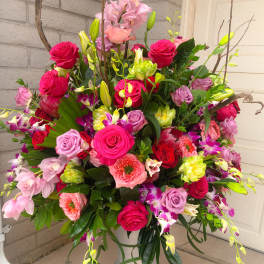 Large mixed floral arrangement in a silver urn vase with pink and red blooms
