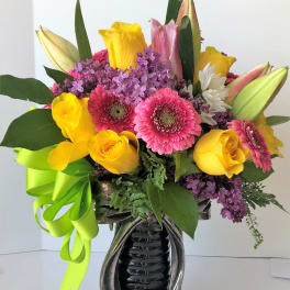 Bright mixed bouquet in a decorative vase with a lime ribbon
