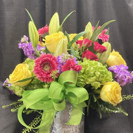 Colorful bouquet of roses, gerbera daisies, lilies, and hydrangeas in a silver vase