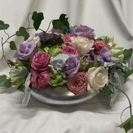 Mixed pink, lavender, and white roses in a low silver bowl