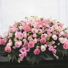 Pink floral casket spray with roses, lilies, and carnations