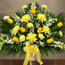 Yellow roses and chrysanthemums in a white vase with a yellow ribbon