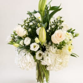 White roses and lilies arranged in a clear glass vase