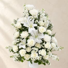 White floral arrangement with roses, lilies, and daisies in a white vase