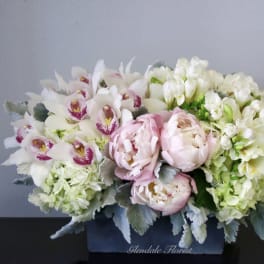 Pink peonies and white orchids in a dark box arrangement