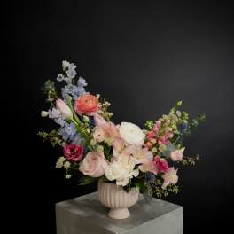 Mixed pink, white, and blue flowers in a ribbed pedestal vase