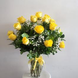 Yellow roses arranged in a clear glass vase with baby's breath