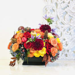 Colorful floral arrangement in a black rectangular vase with roses and dahlias