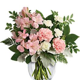 Pink and white flowers arranged in a clear glass vase