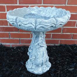 Stone birdbath with rose relief against a brick wall