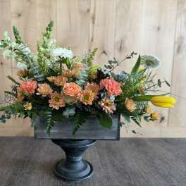 Mixed floral arrangement in a dark wooden container on a pedestal stand