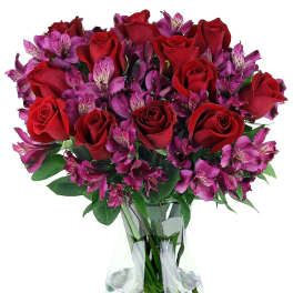 Arrangement of red roses and purple alstroemeria in a clear glass vase