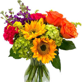 Mixed bouquet with sunflowers, orange roses, and bright blooms in a clear glass vase