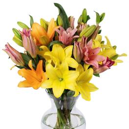 Mixed bouquet of yellow, orange, and pink lilies arranged in a clear glass vase