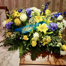 Yellow and white floral spray with a blue "Father" ribbon