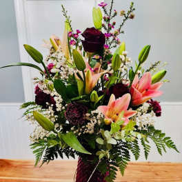 Tall mixed bouquet with pink lilies and dark roses in a vase