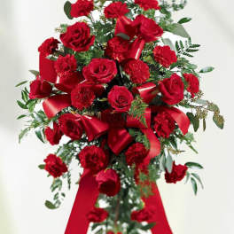 Standing spray of red roses and carnations with red ribbons on an easel