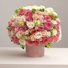Round bouquet of pink and white roses in a pink textured box