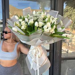 Large bouquet of white roses and tulips wrapped in sheer paper