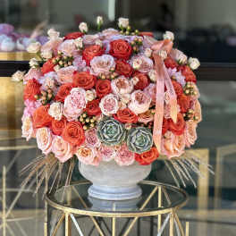 Round bouquet of pink and coral roses in a gray vase