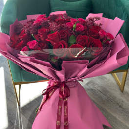 Bouquet of red roses wrapped in pink paper with a ribbon
