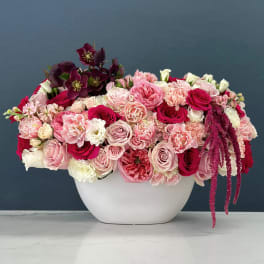 Pink and burgundy floral arrangement in a white vase