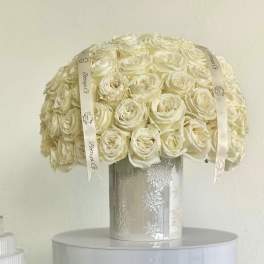 Cream rose bouquet in a silver vase with ribbon accents