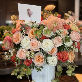 Large bouquet of peach, pink, and white roses in a white vase