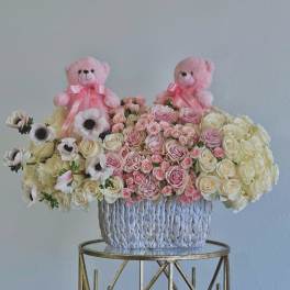 Pink teddy bears above a basket of pink and cream roses and anemones