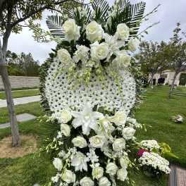 Tall white funeral spray with roses and daisies on a standing easel