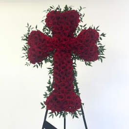 Cross-shaped arrangement of red roses with greenery on a stand