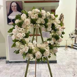 Large white floral wreath on an easel in a church interior