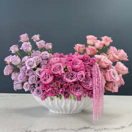Pink and lavender roses arranged in a white vase