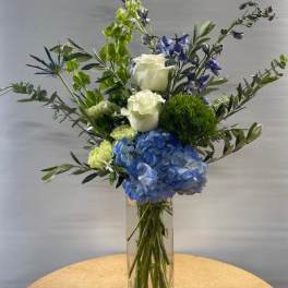 Blue hydrangeas and white roses in a clear glass vase