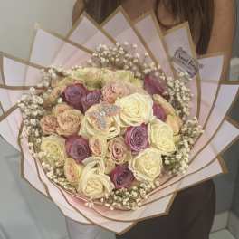 Handheld bouquet of cream, pink, and lavender roses wrapped in pink paper