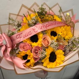Bouquet of sunflowers and pink roses with a pink birthday ribbon