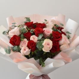 Bouquet of red and pale pink roses wrapped in white paper